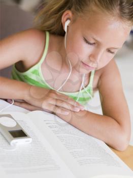 Royalty Free Photo of a Girl Reading a Book and Listening to an MP3 Player