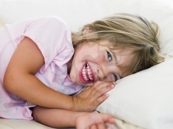 Royalty Free Photo of a Smiling Girl Lying in Bed