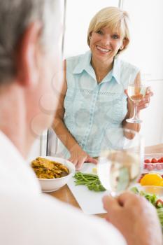 Royalty Free Photo of a Woman Talking to Her Husband While Cooking and Drinking Wine