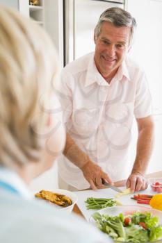 Royalty Free Photo of a Man Preparing a Meal While Talking to His Wife