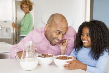 Royalty Free Photo of a Father Having Breakfast With His Daughter and the Mother in the Background