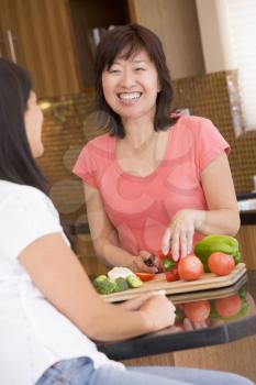 Royalty Free Photo of a Woman Preparing Food While Talking to a Friend
