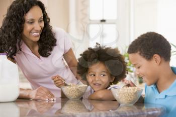 Royalty Free Photo of Children Having Breakfast With Mom Standing Beside Them
