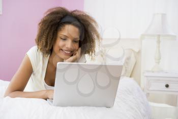 Royalty Free Photo of a Girl on Her Bed With a Laptop