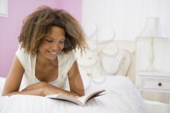 Royalty Free Photo of a Girl Reading a Book in Her Bedroom