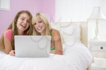 Royalty Free Photo of Two Girls on a Bed With a Laptop