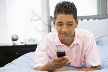 Royalty Free Photo of a Teenage Boy in His Room With a Cellphone