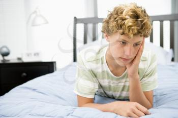 Royalty Free Photo of a Boy Lying on a Bed Looking Sad