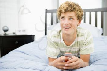 Royalty Free Photo of a Boy With a Cellphone in His Room