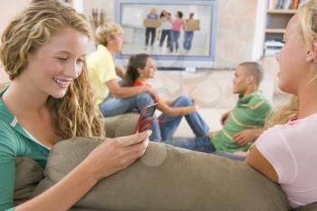 Royalty Free Photo of Teens Watching TV and a Girl on a Cellphone