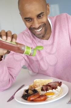 Royalty Free Photo of a Man Eating Bacon and Eggs With Ketchup