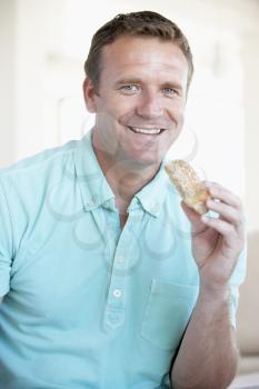 Royalty Free Photo of a Man Eating a Brown Bread Roll