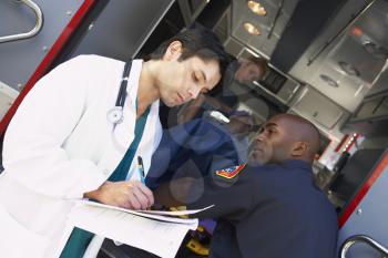 Royalty Free Photo of a Doctor Taking Notes as Paramedic Arrives
