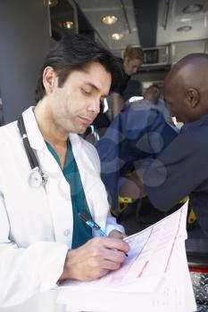 Royalty Free Photo of a Doctor Getting Notes as the Paramedics Unload a Patient