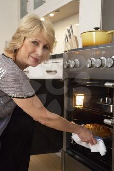 Royalty Free Photo of a Woman Taking Food Out Of an Oven