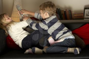 Royalty Free Photo of a Brother and Sister Fighting Over the Remote Control