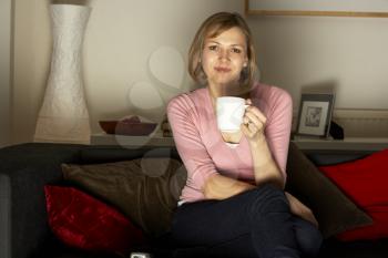 Royalty Free Photo of a Woman Watching TV and Drinking Coffee
