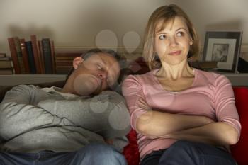 Royalty Free Photo of a Woman Watching TV and Her Husband Asleep