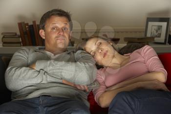Royalty Free Photo of a Couple Watching Television and the Woman Sleeping