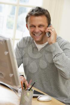 Royalty Free Photo of a Man at a Computer Using a Telephone