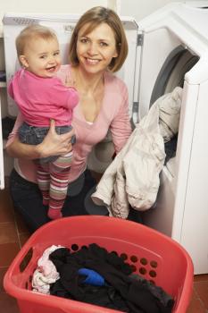 Royalty Free Photo of a Woman Doing Laundry With Her Baby