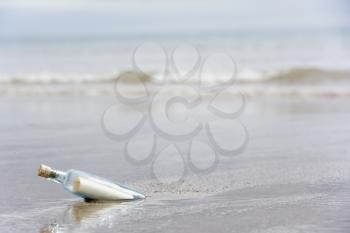 Royalty Free Photo of a Message in a Bottle Buried in Sand on the Beach