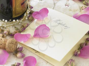 Royalty Free Photo of a Wedding Invitation With a Champagne Bottle and Rose Petal