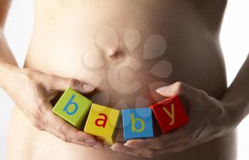 Royalty Free Photo of a Pregnant Woman Holding Blocks That Spell Baby