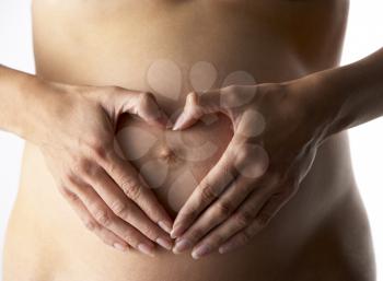 Royalty Free Photo of a Pregnant Woman Forming a Heart Over Her Belly