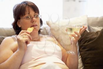 Royalty Free Photo of a Woman With Chips and Wine on the Sofa