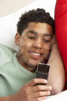 Royalty Free Photo of a Young Boy Lying Down Reading a Text Message
