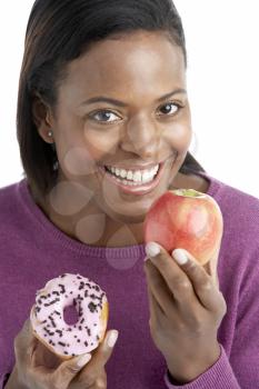 Royalty Free Photo of a Woman Choosing Between an Apple and a Doughnut