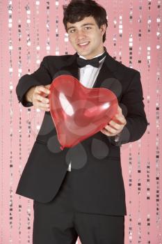 Royalty Free Photo of a Young Man in a Suit Holding a Heart
