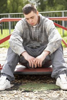 Royalty Free Photo of a Young Man Sitting in a Playground