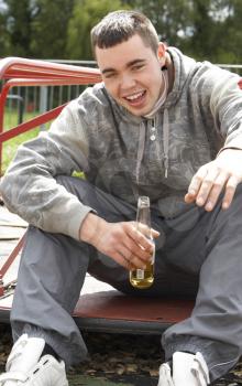 Royalty Free Photo of a Boy in a Playground Drinking Beer