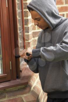 Royalty Free Photo of a Young Man Breaking Into a House
