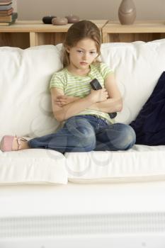 Royalty Free Photo of a Little Girl on a Couch HOlding a Remote Control