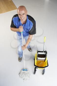 Royalty Free Photo of a Man Mopping an Office Floor