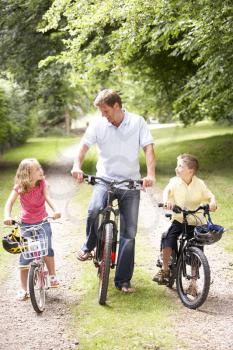 Royalty Free Photo of a Father and Children Riding Bikes