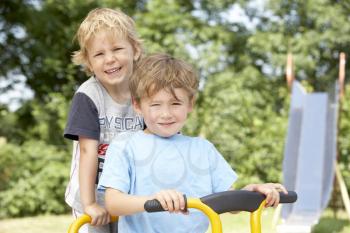 Royalty Free Photo of a Two Boys on a Playground Bike