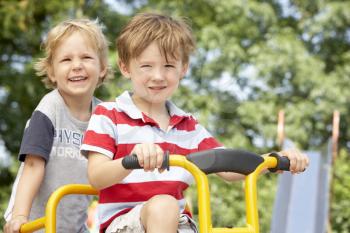 Royalty Free Photo of Two Boys on a Playground Bike