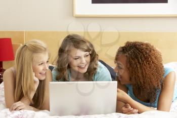 Royalty Free Photo of Three Friends in a Room With a Laptop