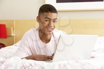 Royalty Free Photo of a Boy on His Bed With a Laptop