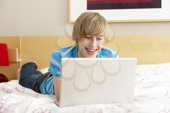 Royalty Free Photo of a Boy on His Bed With a Laptop