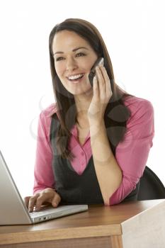 Royalty Free Photo of a Woman at a Computer With a Cellphone
