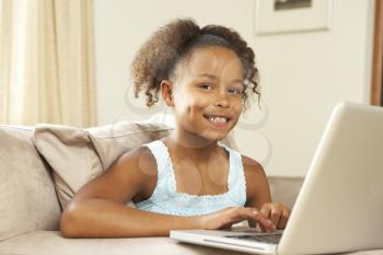 Royalty Free Photo of a Little Girl at Home With a Laptop