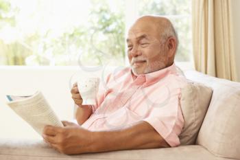 Royalty Free Photo of a Man Reading a Book and Drinking Coffee