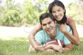 Royalty Free Photo of a Couple on the Ground With a Football