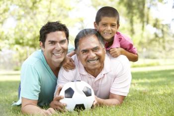 Royalty Free Photo of Three Generations of Men on the Ground With a Soccer Ball
