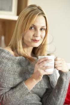 Portrait Of Young Woman Sitting On Sofa With Cup Of Coffee